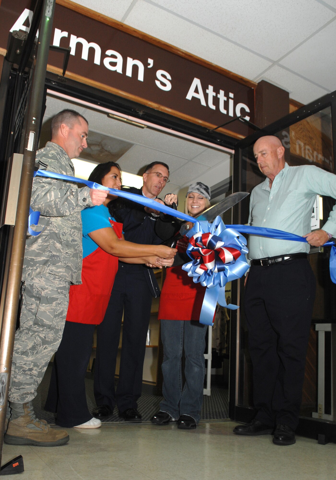 Brig. Gen. Scott Vander Hamm, 509th Bomb Wing commander, and members of the Airman's Attic direction board, cut a ribbon signifying the reopening of the facility, Tuesday. The Airman's Attic has been revamped with new paint and carpet.(U.S. Photo by Airman 1st Class Cody H. Ramirez)(Released)
