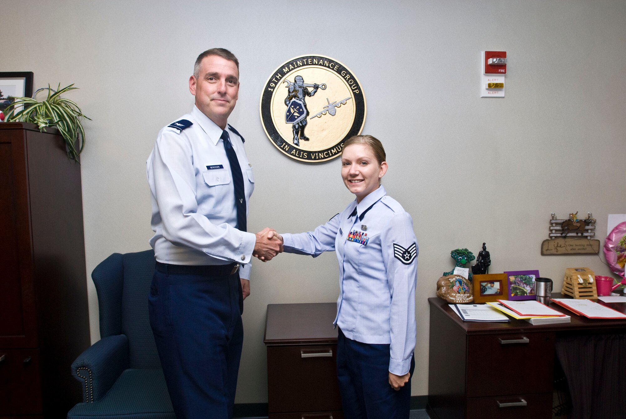 Col. Mike Minihan (left), 19th Airlift Wing commander, presents a coin Monday to Staff Sgt. Misty Atkin, 19th Maintenance Group knowledge operator, for her selection as the Combat Airlifter of the Week. Sergeant Atkin conducted Sharepoint training with 12 Airmen, increasing the number of qualified users within the group. (U.S. Air Force photo by Staff Sgt. Nestor Cruz)