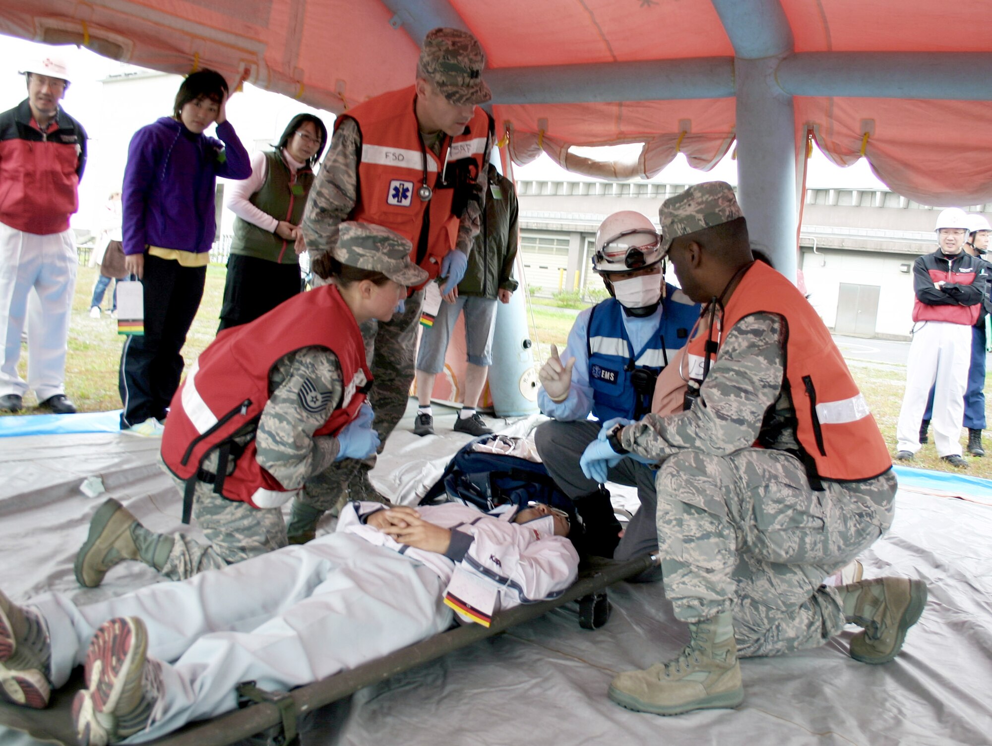 Capt. Michael Brough, Tech. Sgt. Sarah Ortega-Russell and Maj. Mario Maxwell, discuss a simulated earthquake victim's injuries with a Japanese first responder Oct. 3 at Misawa City Sea Port during the 2010 Misawa City Disaster Drill. The bilateral exercise included Misawa City and Aomori Prefecture government agencies, Japanese Ground and Air Self-Defense Forces in northern Japan, and 35th Fighter Wing personnel. Captain Brough, Sergeant Ortega-Russell and Major Maxwell are emergency responders with the 35th Medical Operations Squadron. (U.S. Air Force photo/Tech. Sgt. Kelly White)