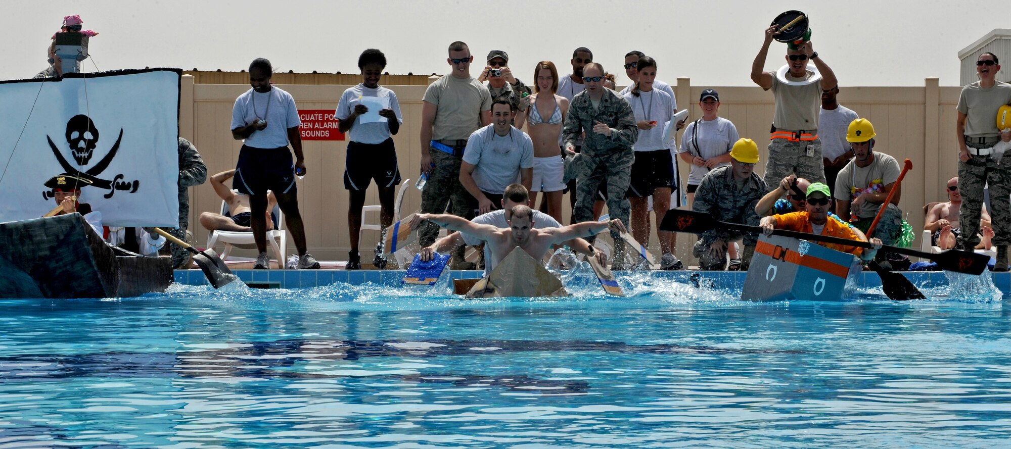 SOUTHWEST ASIA - Airmen from the 386th Air Expeditionary Wing race to the other side of the base pool during the Tip Top Boat Tournament, sponsored by the 386th Expeditionary Force Support Squadron Oct. 2, 2010. Units from across the base were tasked with creating and racing boats made only of cardboard, duct tape and rubber bands. (U.S. Air Force photo by Senior Airman Laura Turner)