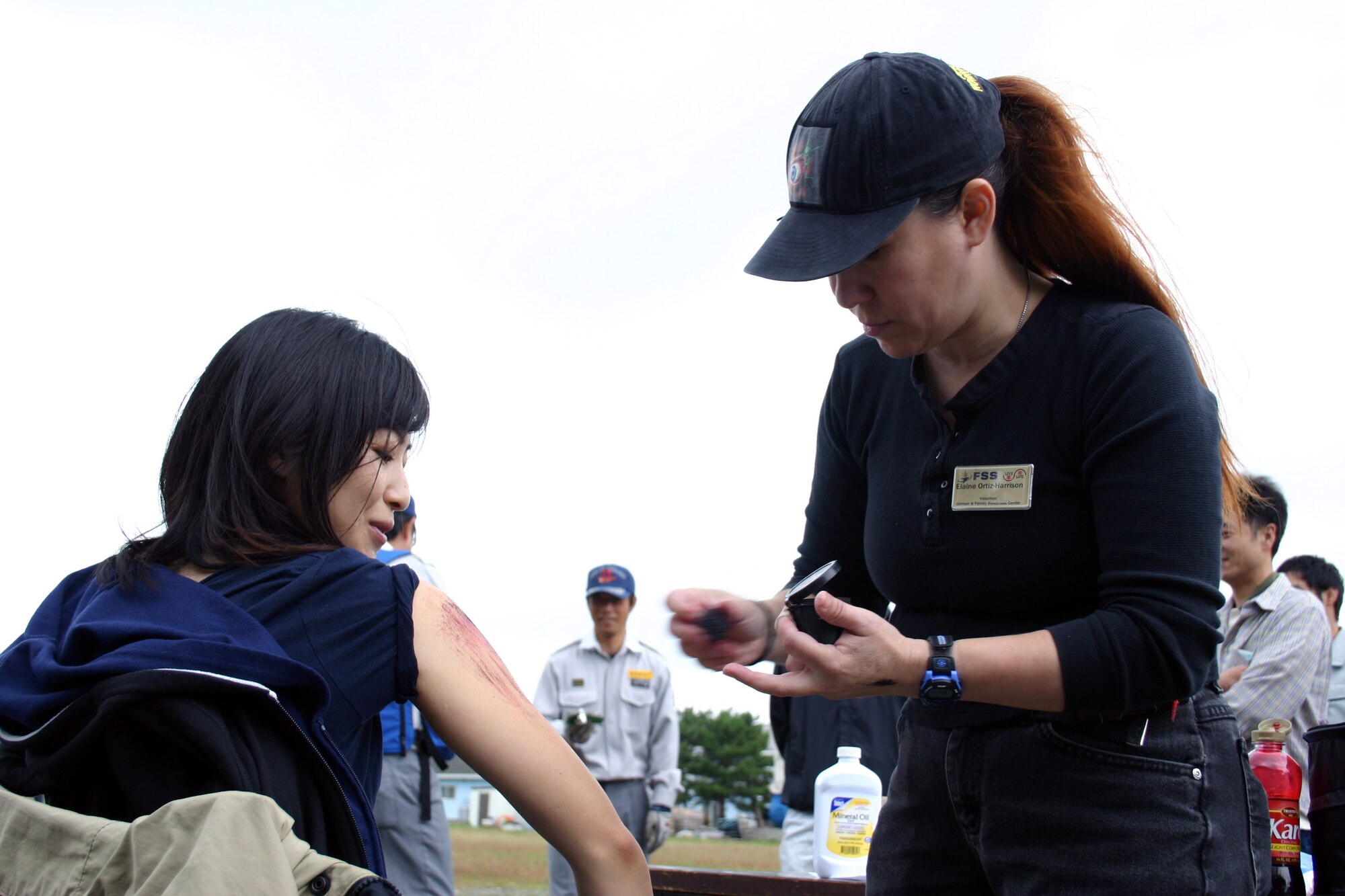 Misawa Air Base member, Elaine Ortiz-Harrison, applies moulage to a Japanese exercise roll player Oct. 3, 2010, at Misawa City Sea Port, Japan. The simulated injury resulted from a natural disaster scenario that tested the capabilities and cooperation efforts of Misawa City and Aomori Prefecture governmental agencies, Japanese Ground and Air Self-Defense Forces in northern Japan, and the 35th Fighter Wing. (U.S. Air Force photo by Tech. Sgt. Kelly White/Released)