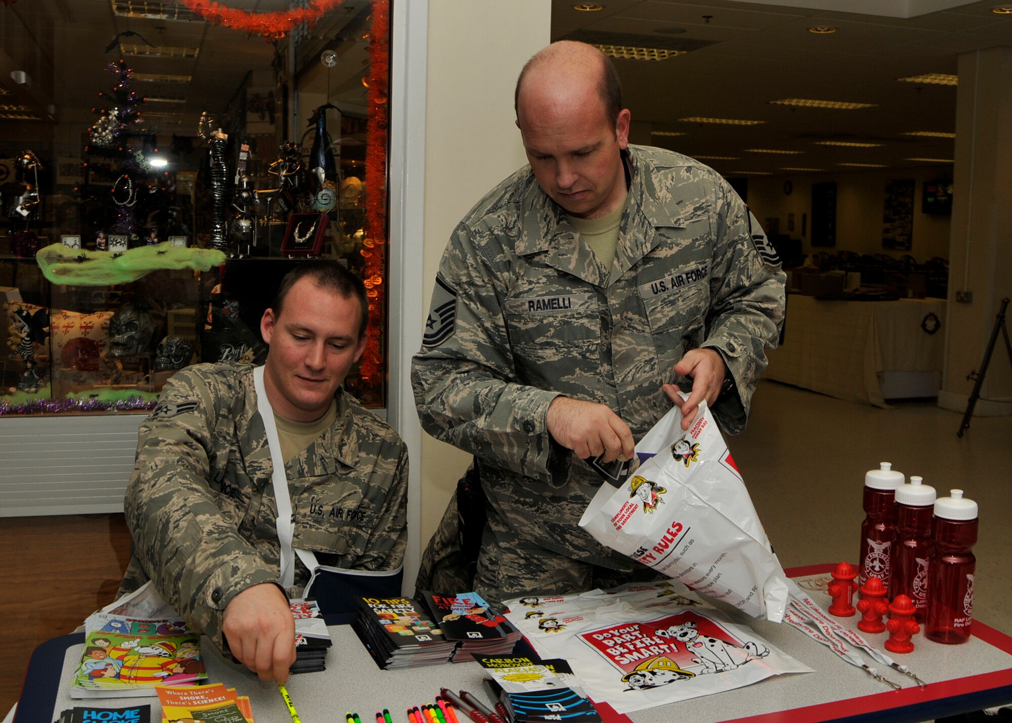 ROYAL AIR FORCE LAKENHHEATH, England - (left to right) Airman First Class Nicholas Lawrence, 48th Civil Engineer Squadron firefighter, and Master Sgt. Kenneth Ramelli, 48th CES fire inspector, fill a bag with fire safety pamphlets, pencils and other items at the base exchange here during National Fire Prevention Week on Oct. 4. The goal of National Fire Prevention Week is to raise awareness and provide the community with information to help prevent fires. (U.S. Air Force photo/Airman 1st Class Tiffany M. Deuel) 