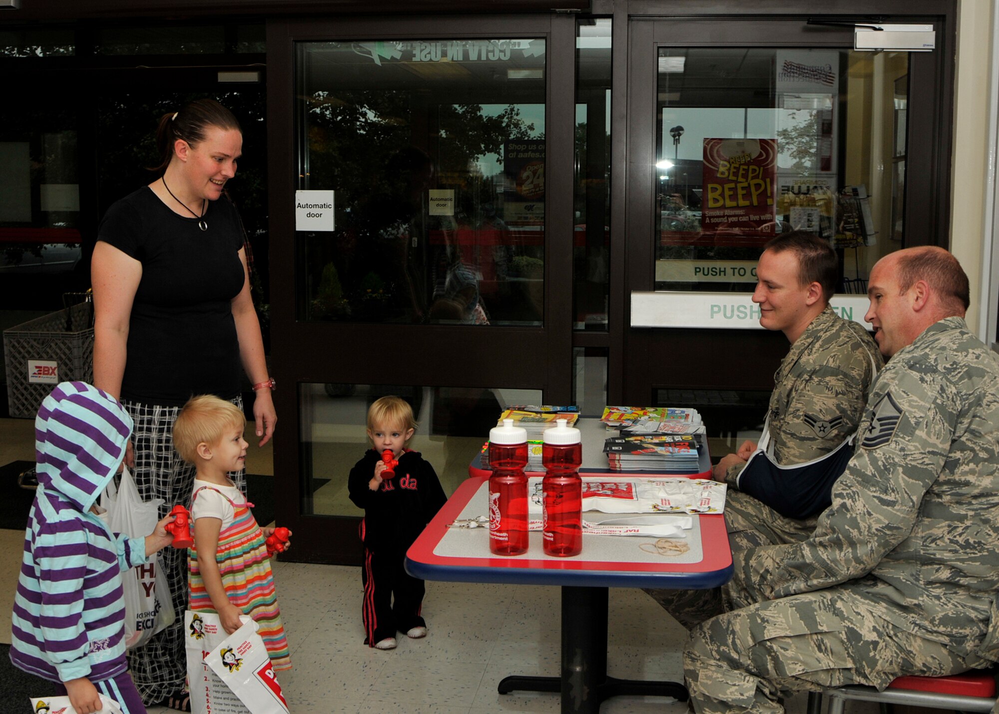 ROYAL AIR FORCE LAKENHHEATH, England - (left to right) Alex, Hailey, Tia and their mother Debra Wolf, Air Force civilian dependents, receive foam fire hydrants and informative pamphlets from Airman 1st Class Nicholas Lawrence, 48th Civil Engineer Squadron firefighter, and Master Sgt. Kenneth Ramelli, 48th CES fire inspector, at the RAF Lakenheath Base Exchange during National Fire Prevention Week on Oct. 4. Along with the information kiosk, the week will also include fire extinguisher training sessions, a vehicle extrication demonstration, visits to the child development centers by Sparky the Fire Dog and many other events. (U.S. Air Force photo/Airman 1st Class Tiffany M. Deuel) 