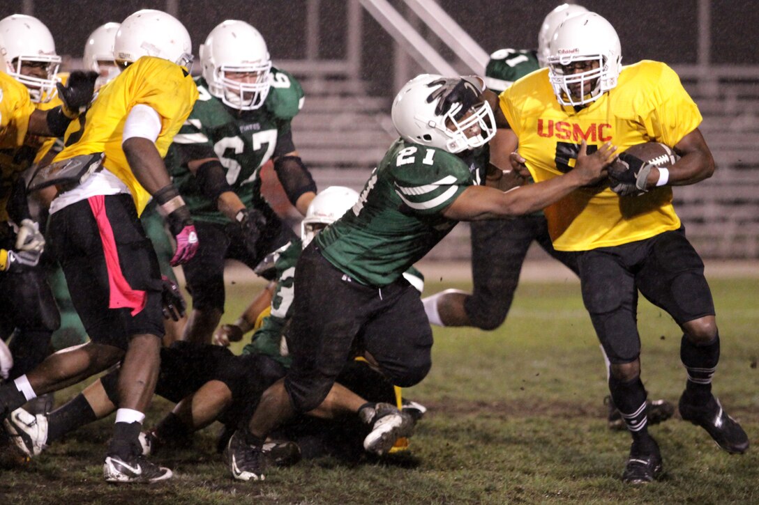 Running back Danniel Alexander, 1st Marine Logistics Group "Beasts" pushes through the defensive line of Weapons Field Training Battalion "Raiders" during a regular season game of the USAA Pendleton Cup Football League at Camp Pendleton's Paige Field house, Oct.5.