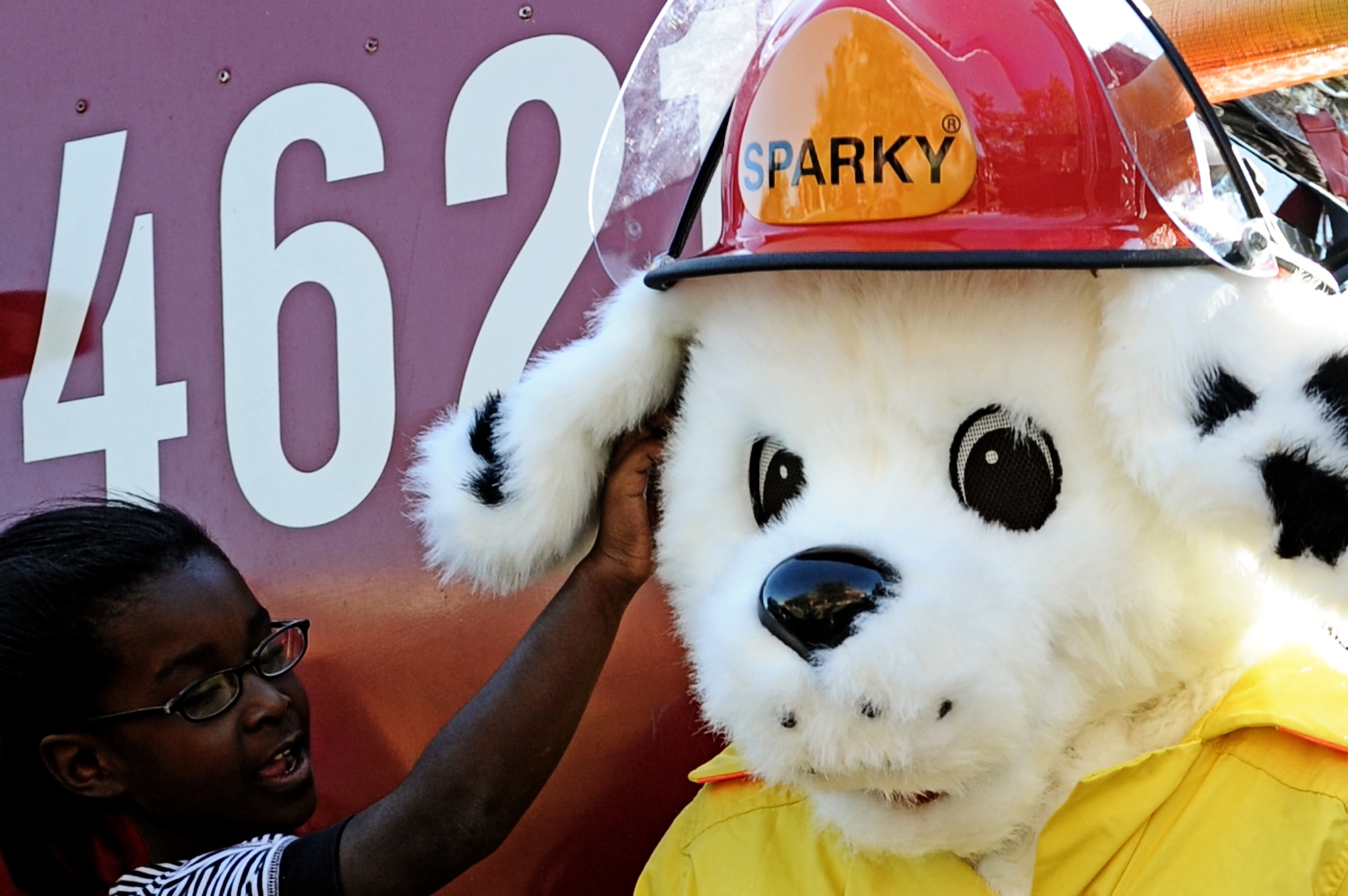 A child from the Youth Center scratches behind Sparky the Fire Dog's ear Oct. 5. In honor of Fire Safety Awareness Week, the Scott Air Force Base Fire Department will provide fire safety awareness education and training throughout the week of Oct. 3-9. (U.S. Air Force photo/Staff Sgt. Brian J. Valencia)