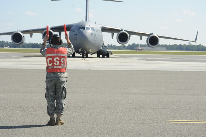 Airman 1st Class Cody Shokoui directs a Charleston C-17 aircraft, tail number 21099, at the start of the day, as his team gears up to perform inspections and maintenance that may be needed on the plane, Tuesday, Oct. 5. Airman Shokoui is attached to the 437th Aircraft Maintenance Squadron onboard Joint Base Charleston-Air Base. (U.S. Navy photo/Mass Communication Specialist 1st Class Jennifer Hudson)