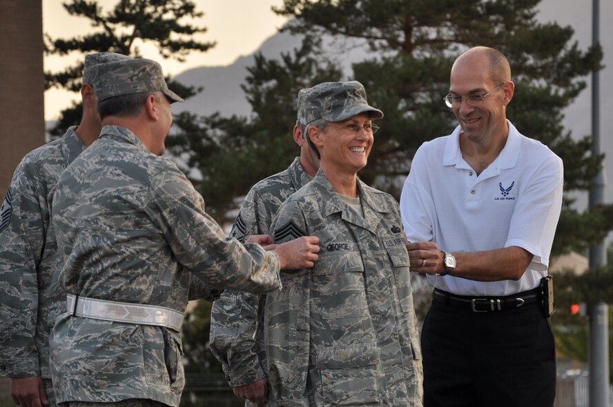 Chief Master Sgt. Cindy George smiles as she has her new command chief insignia "pinned on" by 419th Fighter Wing Commander Col. Walter "Buck" Sams and her husband, Capt. (retired) Dale George during her promotion ceremony Oct. 3. (U.S. Air Force photo/Staff Sgt. Alan Schultz)