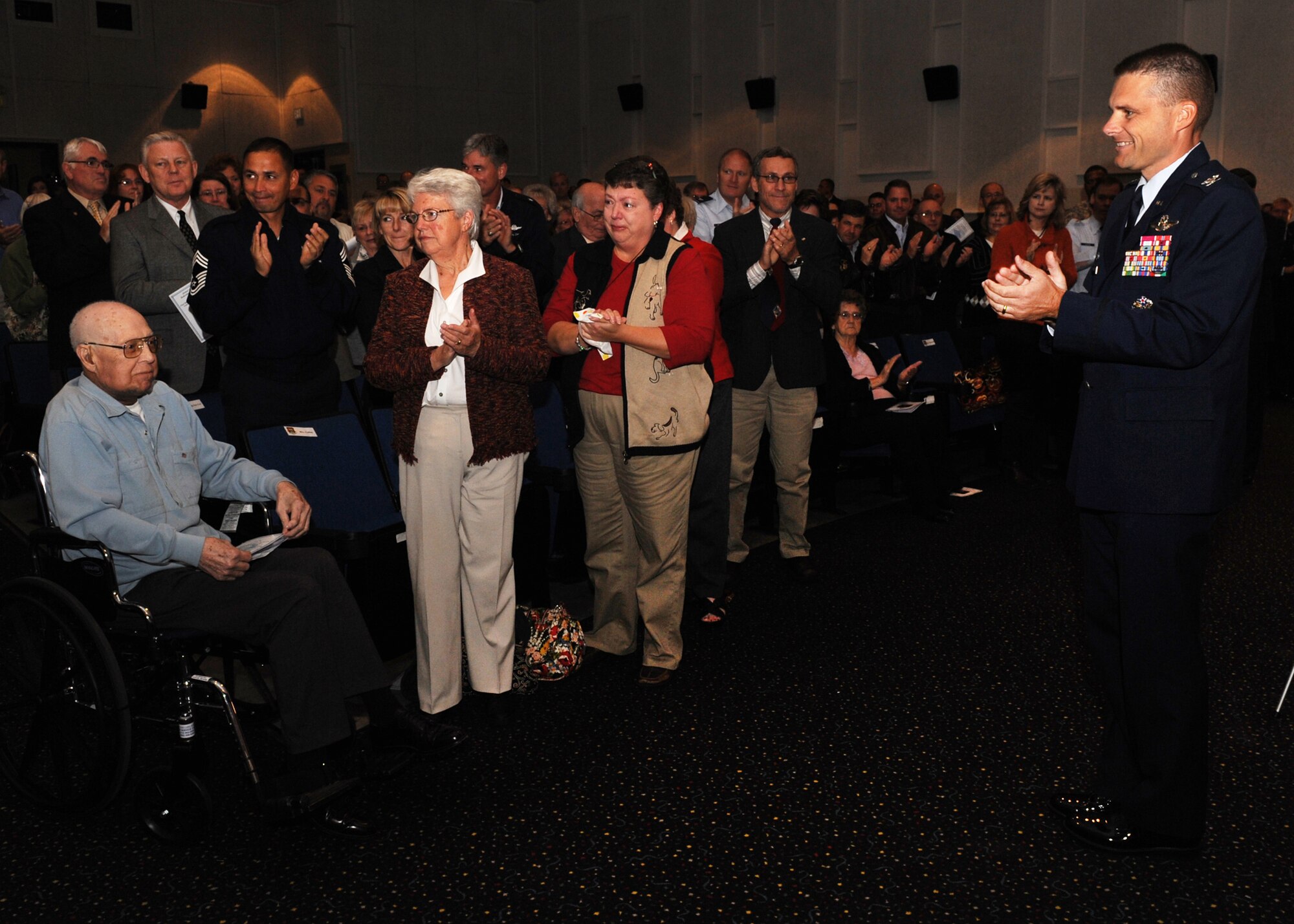 SCOTT AIR FORCE BASE, Ill. -- Members of Team Scott give Retired Chief Master Sergeant Gene Collins a standing ovation after he received a plaque dedicating the Airman’s Attic to him.  Mr. Collins began volunteering at Airman’s Attic in 2004. (U.S. Air Force photo/Senior Airman Tristin English)