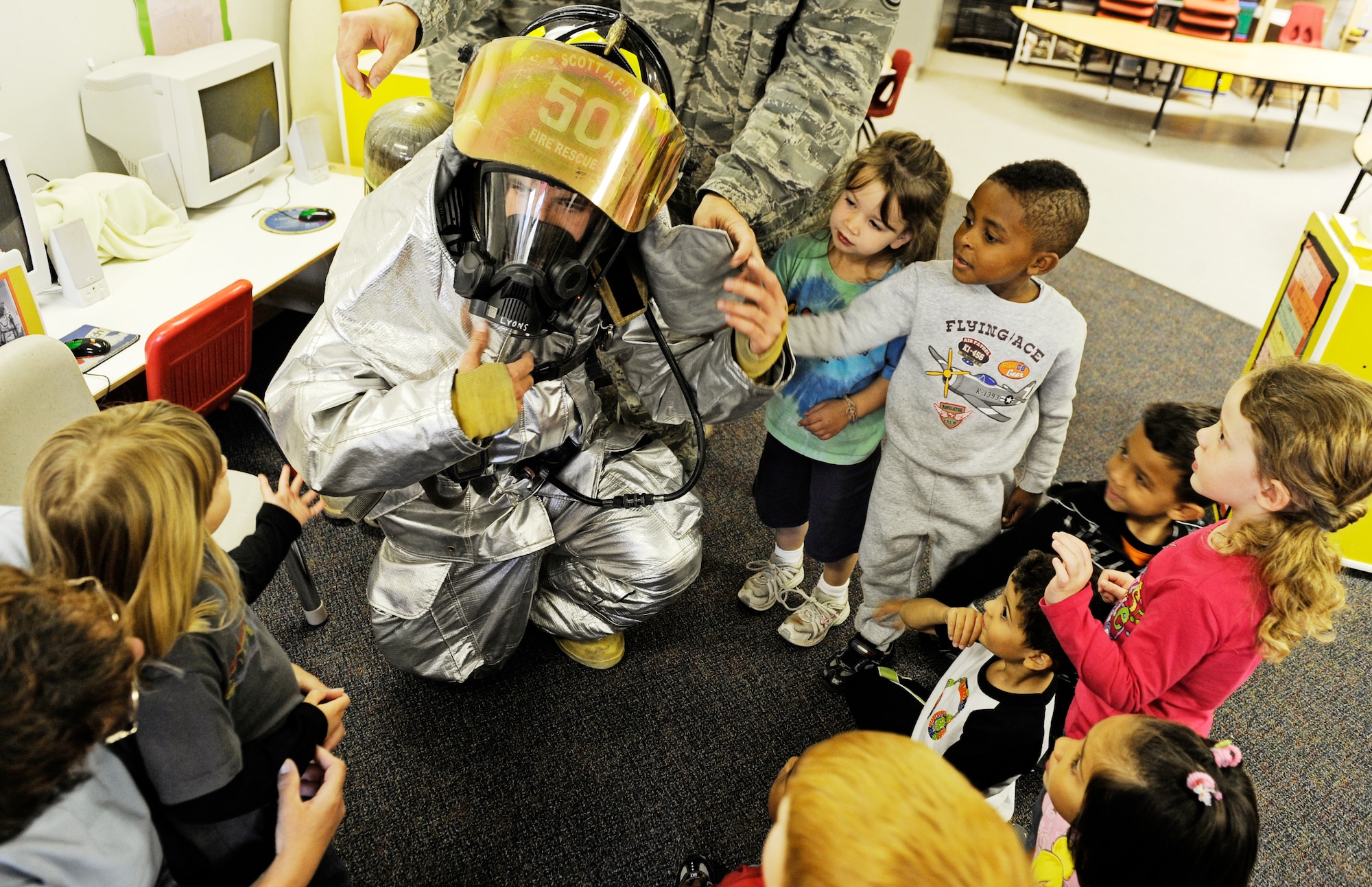 Airman 1st Class Jeff Lyons, 375th Civil Engineer Squadron firefighter, lets children from the three- to five-year-old age group at the Child Development Center see his fire suit up close to help show them that firefighters are not scary Oct. 5. In honor of Fire Safety Awareness Week, the Scott Air Force Base Fire Department provided fire safety awareness education and training throughout the week of Oct. 3-9. (U.S. Air Force photo/ Staff Sgt. Ryan Crane)