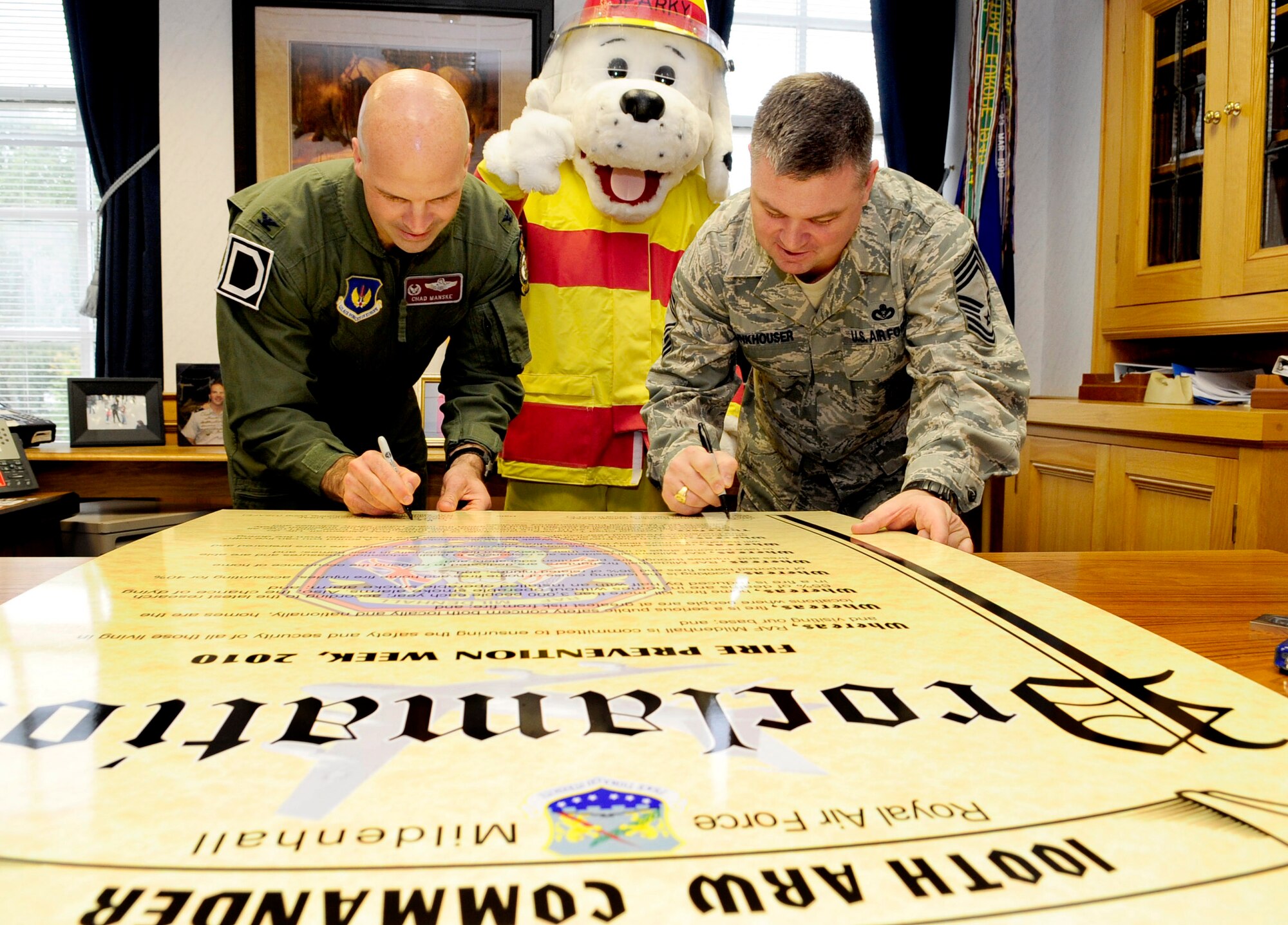 RAF MILDENHALL, England -- Col. Chad Manske, 100th Air Refueling Wing commander, and Chief Master Sgt. Charles Funkhouser, 100th Civil Engineer Squadron fire chief, sign the Fire Prevention Week Proclamation here Oct. 1.  The main message that the firefighters are pushing this year is " BEEP BEEP BEEP a sound you can live with." The message pertains to the importance of working fire alarms in each home to help ensure safety and prevent casualties. (U.S. Air Force photo/Senior Airman Ethan Morgan)