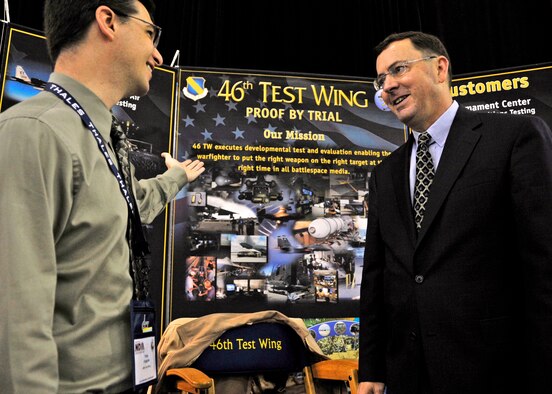 Toby Higgins, 46th Test Wing Plans Office, briefs Dr. Steve Butler, Executive Director, Air Force Materiel Command, on the wing’s latest technology during the Air Armament Symposium. This year's 36th annual two-day symposium highlighted topics vital to national and international defense interests. Speakers from joint services and Air Force major commands shared the common thread of working together in a changing acquisition world.  (U.S. Air Force photo/Samuel King Jr.)