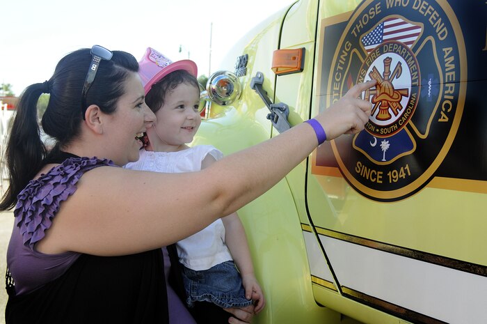 Charlotte Matthews shows her daughter, Lorelai, 3, the firefighters? symbol on one of the many fire trucks displayed during the fire prevention fair on Joint Base Charleston-Weapons Station, S.C., Oct. 5, 2010. Lowcountry area firefighters provided tours and answered questions from patrons throughout the event, as well as providing fire prevention tips onboard JB CHS-WS. The event, held in recognition of National Fire Prevention Week, stressed the importance of fire safety and increasing awareness in the Charleston area. (U.S. Navy photo by Mass Communication Specialist 1st Class Jennifer R. Hudson/released)