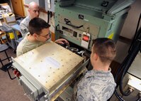 MINOT AIR FORCE BASE, N.D. -- Airman 1st Class Brian Ellis, 91st Missile Maintenance Squadron missile radio technician, inspects a cable connector as Senior Airman Nathan Hendricks, 91st MMXS missile radio technician, secures a cable to the back of the terminal electronics unit while being observed by Staff Sgt. Matthew Owen, 91st MMXS missile radio team chief, here Oct.4. The TEU is a part of the minuteman minimum essential emergency communications network program. Programs like these are crucial to the mission of all Airmen assigned to Air Force Global Strike Command. (U.S. Air Force photo by Staff Sgt. Keith Ballard)