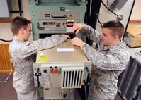MINOT AIR FORCE BASE, N.D. -- Airman 1st Class Brian Ellis, 91st Missile Maintenance Squadron missile radio technician, inspects a cable connector as Senior Airman Nathan Hendricks, 91st MMXS missile radio technician, secures a top cover to the back of the terminal electronics unit here Oct.4. The TEU is a part of the minuteman minimum essential emergency communications network program. Programs like these are crucial to the mission of all Airmen assigned to Air Force Global Strike Command. (U.S. Air Force photo by Staff Sgt. Keith Ballard)
