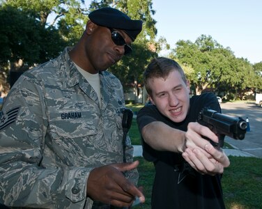 Tech Sgt William Graham from the 902 Security Forces Squadron instructs Kiefer Muller on the operation of the M-9 pistol during the Randolph National Night Out celebration on October 5 2010. Randolph Security Forces and Fire Department were on hand to educate people on how they can help fight crime in residential neighborhoods.  
(U.S. Air Force Photo By Don Lindsey)