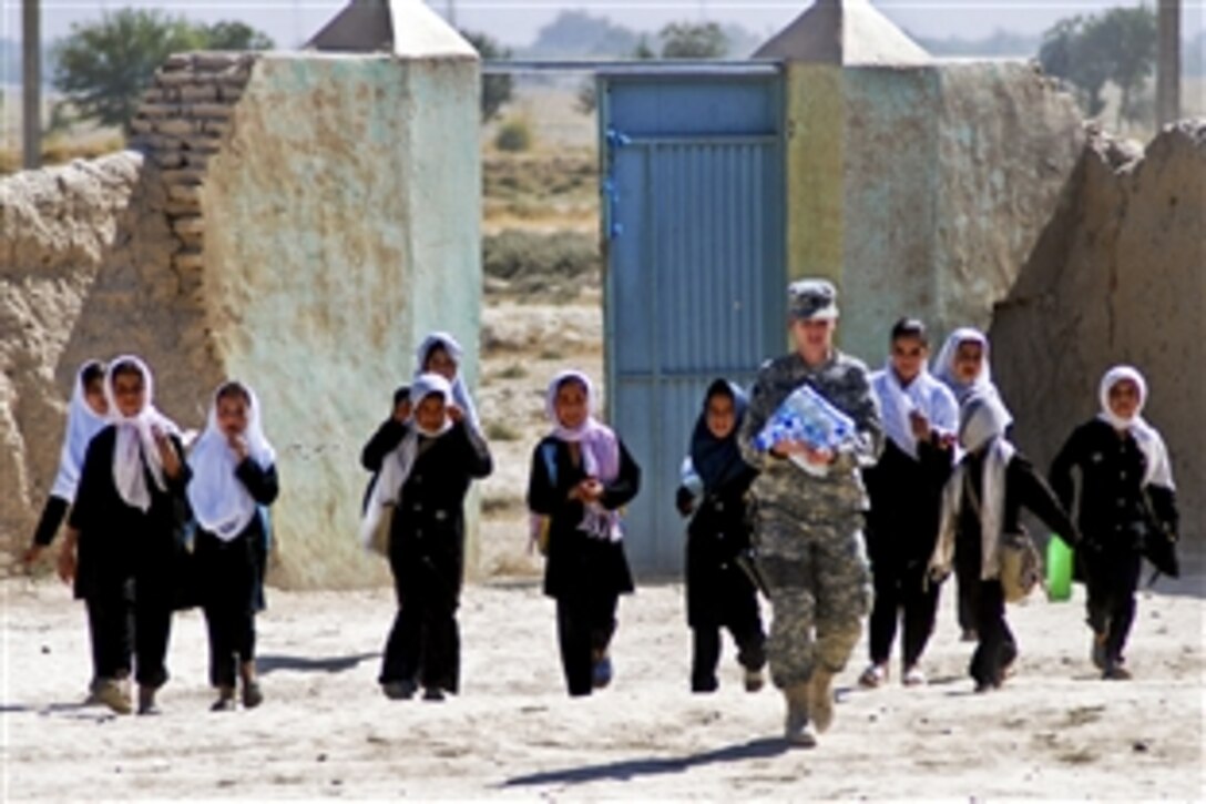 U.S. Army Capt. Lisa Kirby leads a group of Kaka Kot School children to the center of the school where the Afghan National Army's 209th Corps and the U.S. Army's 10th Mountain Division's Female Engagement Team wait to donate about $3,000 worth of school supplies to the students in the Nahr-e Shahi district, Afghanistan, Oct. 4, 2010. Kirby is the engagement team coordinator for the 10th Mountain Division on Camp Mike Spann, Afghanistan.
