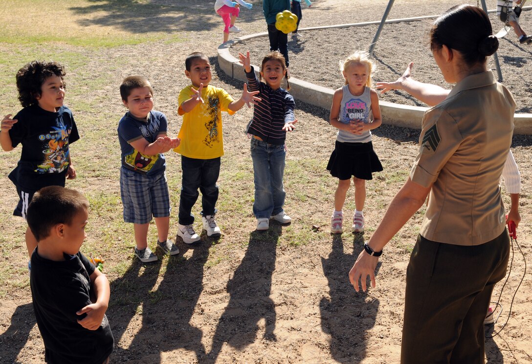 Sgt. Krystal Chatham, Marine Attack Squadron 214 intelligence analyst, plays catch with a group of kindergarten students at C.W. McGraw Elementary School, in Yuma, Ariz., Oct. 6, 2010. The Blacksheep adopted the school as part of the Adopt-a-School Program. They plan to visit the school every Wednesday to promote literacy and scholastic achievement, and engage in various activities with students from every grade level at the school.