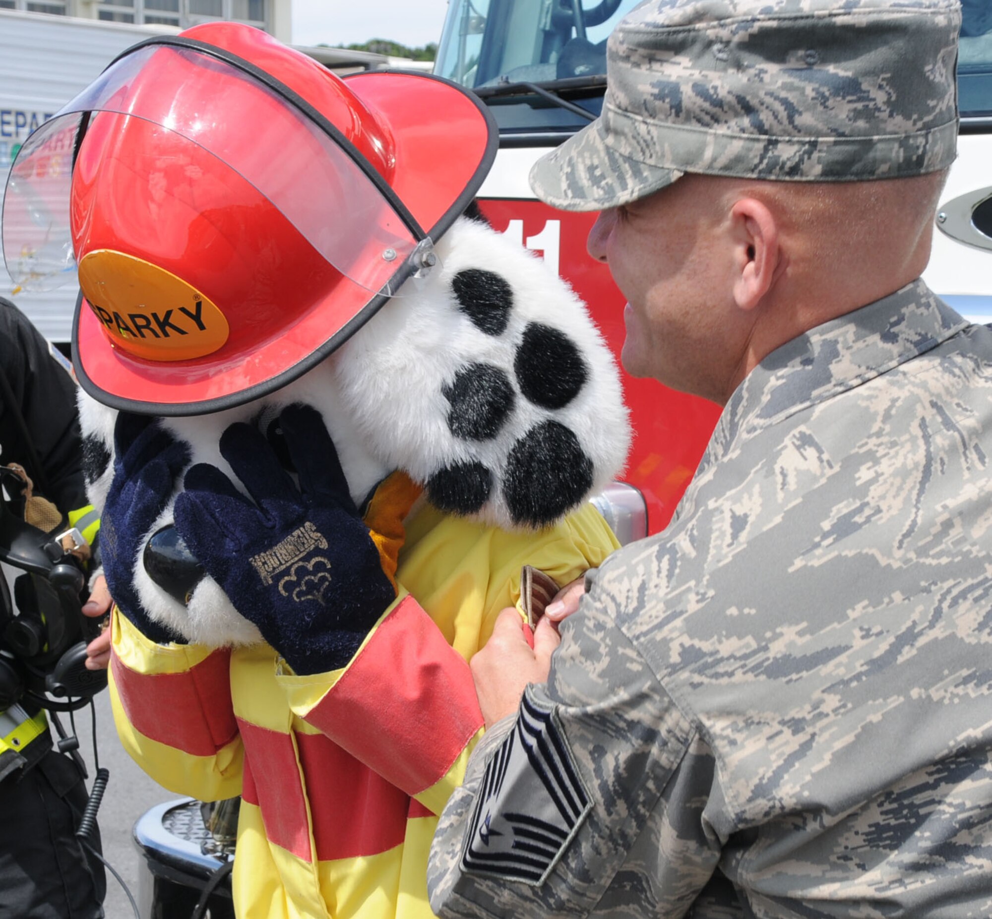 Sparky the Fire Dog braces for the tacking on of his staff sergeant stripes by Kadena fire chief, Chief Master Sgt. Christopher Mohr, in a promotion at Kadena Elementary School Oct. 7. Sparky has educated and entertained more than 215,000 children across Kadena since 1988.  (U.S. Air Force photo by Tech. Sgt. Mike Tateishi)
