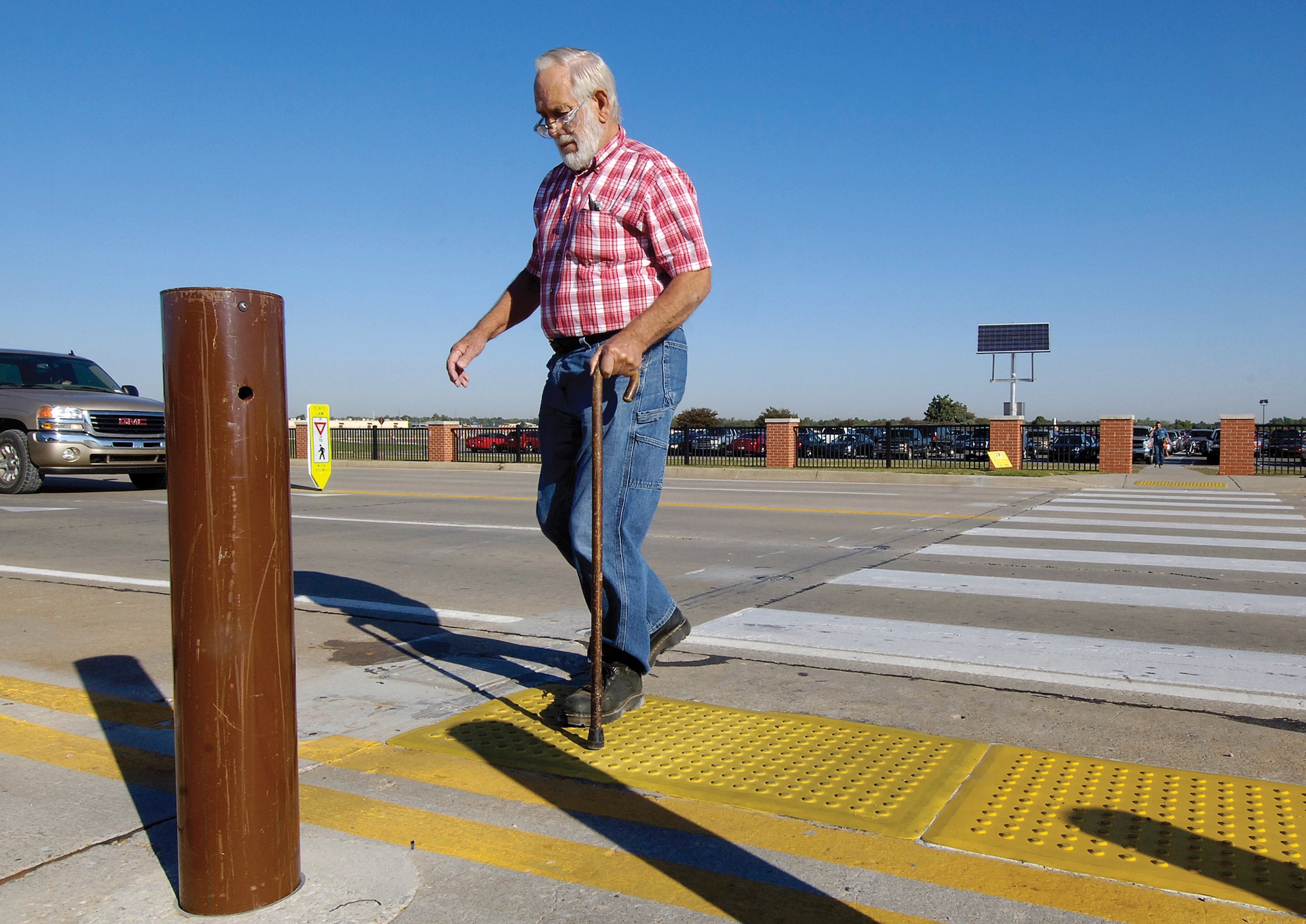 A new crosswalk north of Bldg. 3001 uses solar energy to activate warning lights.  Dale Eaton, a machinist in the 548th Propulsion Maintenance Squadron, crosses where step-activated yellow pads turn on blinking ground lights that alert motorists to pedestrians.  (Air Force photo by Margo Wright)