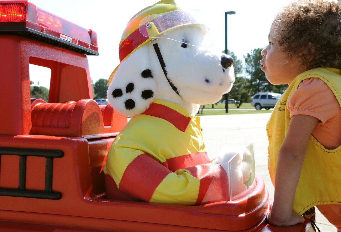 LANGLEY AIR FORCE BASE, Va. – Annabella Esquilin, daughter of Katherine Gielinin, learns about fire safety from Sparky the fire dog Oct. 7. Base firefighters are teaching children about fire safety during Fire Prevention Week, Oct. 3-9.  Events and activities promoting fire safety and prevention end this weekend with Saturday’s fire department open house. (U.S. Air Force photo/Staff Sgt. Tabitha Kuykendall) (released)