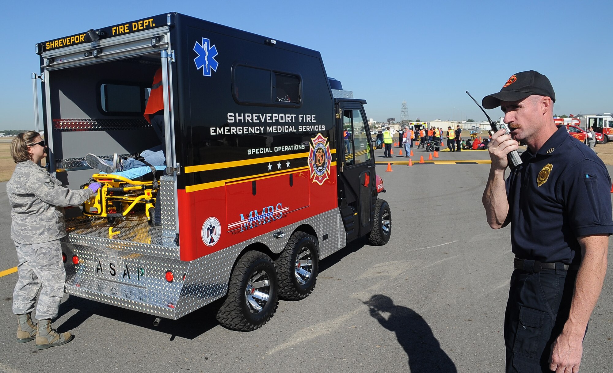 BARKSDALE AIR FORCE BASE, La. -- As a Barksdale medical technician checks on a victim, a Shreveport fire technician calls in the emergency transport during a full-scale disaster drill at the Shreveport Regional airport Oct. 6. More than 60 simulated victims were either listed as deceased or injured and Bossier City, Shreveport and Caddo law enforcement, fire department and emergency medical technicians arrived on scene to assist. The exercise provided training and an opportunity for Barksdale Airmen to work with other emergency units.  (U.S. Air Force photo/Senior Airman Amber Ashcraft) (RELEASED)