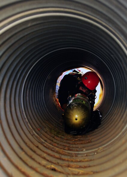 DYESS AIR FORCE BASE, Texas -- Airman 1st Class Anthony Guajardo, 7th Civil Engineer firefighter, pushes his air tank through a small tunnel to make climbing through easier during a training exercise at Dyess Air Force Base, Texas, Oct. 6. Emergency responders are often called to situations that require climbing or propelling into small spaces in order to retrieve the bodies of dead or injured people due to the hazards of ditches or uncontrolled working areas. (U.S. Air Force photo/ Senior Airman Domonique Washington) 
