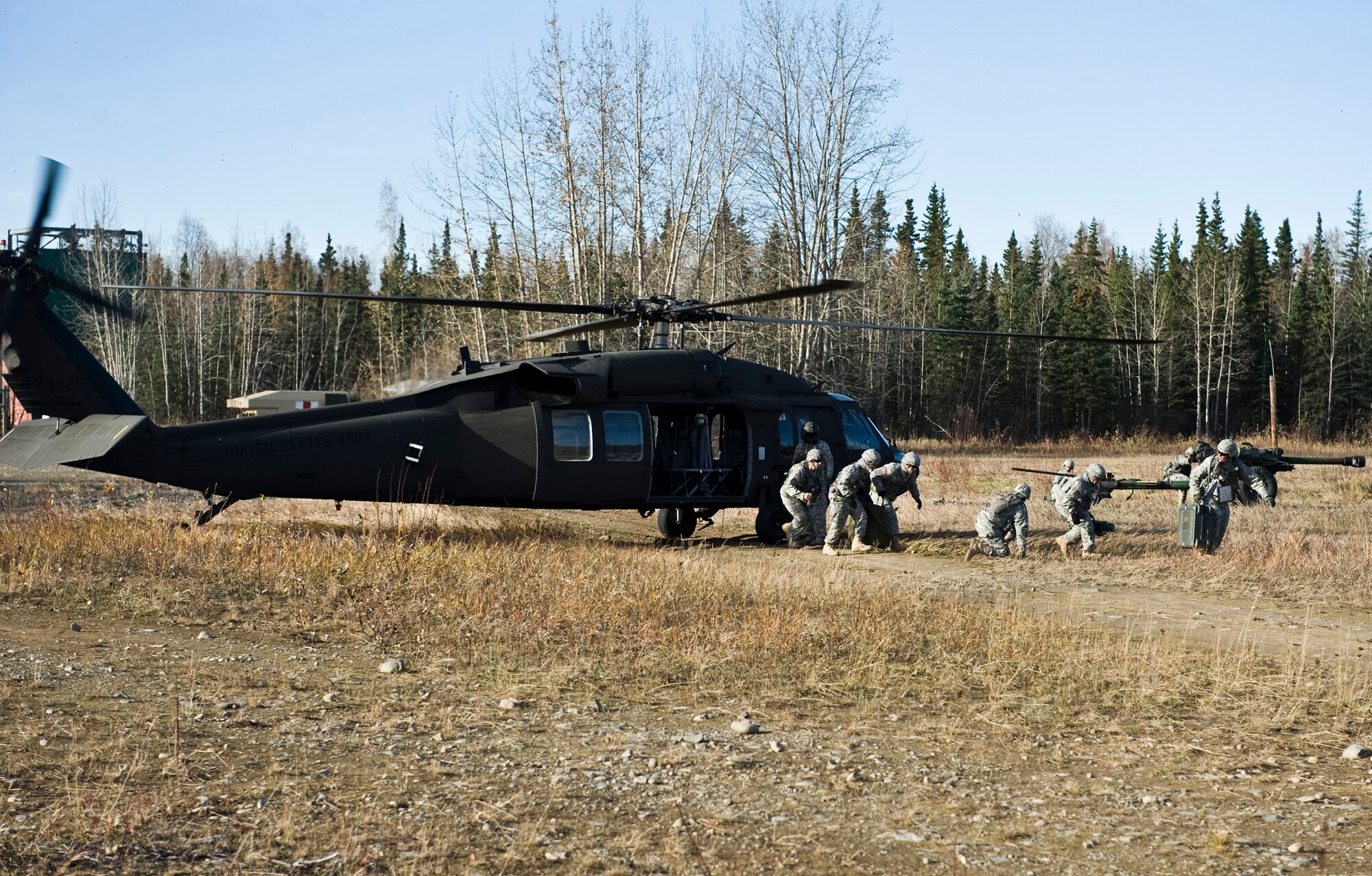 JOINT BASE ELMENDORF-RICHARDSON, Alaska -- Soldiers of the Alpha Battery from the 2nd Battalion of the 377th Parachute Field Artillery Regiment duck for cover as an Army UH-60 Black Hawk takes off Oct. 5. Members of the 2-377th PFAR simulated a two-gun raid, firing into "enemy territory," as part of some mission-ready training. They used M119 105 mm howitzers which were sling loaded to the Black Hawk as part of the training. (U.S. Air Force photo/Airman 1st Class Christopher Gross)  