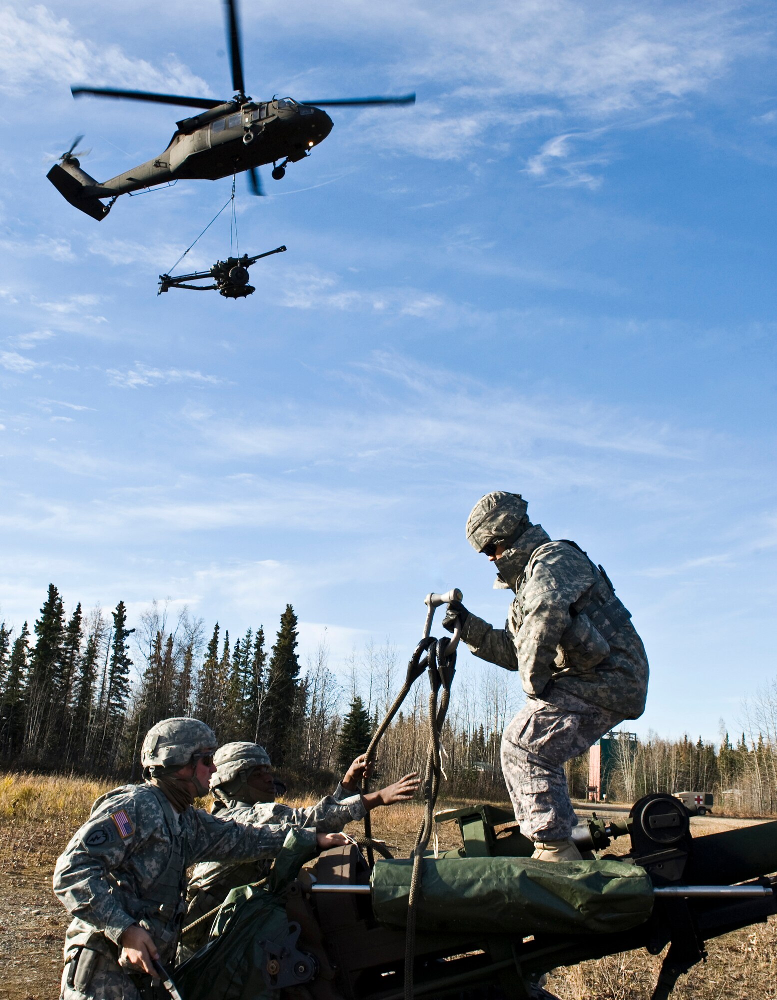 JOINT BASE ELMENDORF-RICHARDSON, Alaska -- Soldiers of the Alpha Battery from the 2nd Battalion of the 377th Parachute Field Artillery Regiment work on setting up their M119 105 mm howitzer as an Army UH-60 Black Hawk flies with a M119 105 mm howitzer sling loaded to it Oct. 5. Members of the 2-377th PFAR simulated a two-gun raid, firing into "enemy territory," as part of some mission-ready training. (U.S. Air Force photo/Airman 1st Class Christopher Gross)  