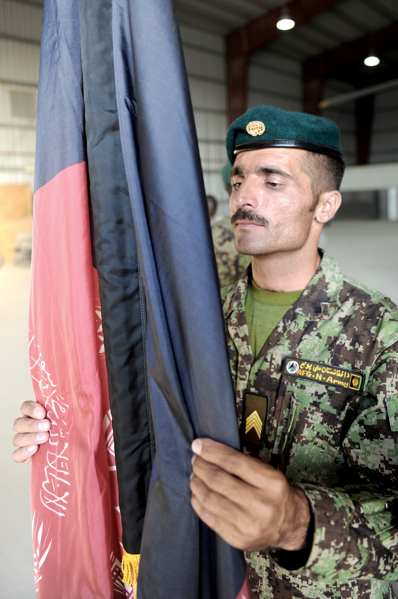 An Afghan airman for the Kandahar Air Wing adjusts the flag during posting of the colors Oct. 3, 2010, at Kandahar Airfield, Afghanistan. The 451st Air Expeditionary Wing Honor Guard members worked with the Afghans to help them prepare their own Honor Guard for a ceremony marking the one year anniversary of the Kandahar Air Wing. (U.S. Air Force photo/Tech. Sgt. Chad Chisholm)