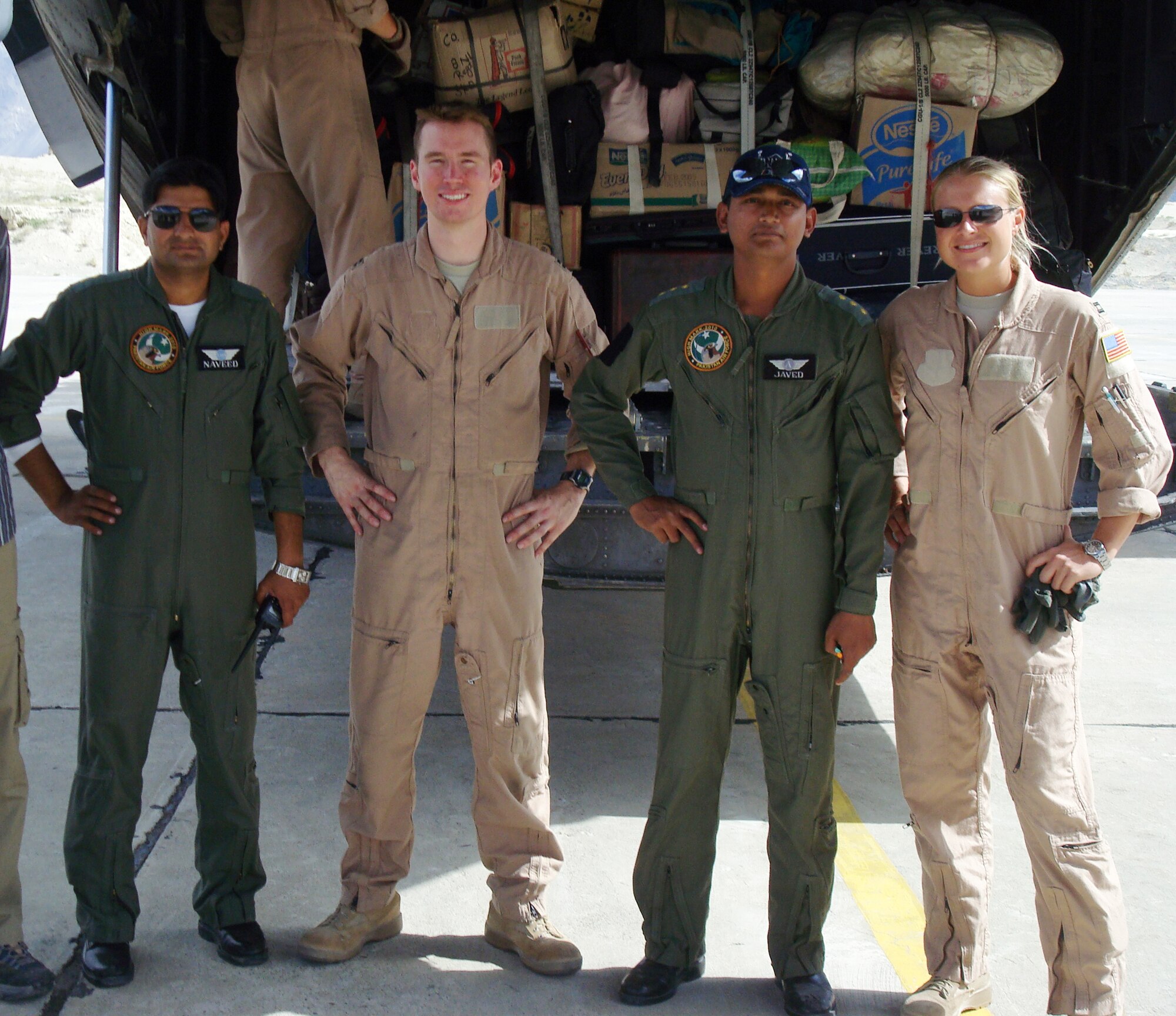 SOUTHWEST ASIA -- Aircrew members from the 737th Expeditionary Airlift Squadron, including pilots Capt. Daniel Hilferty (second from left) and Capt. Erin Van Oosten (far right), work in partnership with Pakistani military personnel at Skardu Airport, Pakistan, Sept. 5, to transport Pakistani citizens displaced by record flooding to safer locations throughout the country. The 737th EAS and 386th Air Expeditionary Wing deployed multiple C-130 aircraft and more than 80 personnel in response to the disaster, airlifting more than 1,000 tons of relief supplies and 500 displaced persons between Aug. 30, 2010, and Oct. 1, 2010, when the squadron's role in the mission concluded.