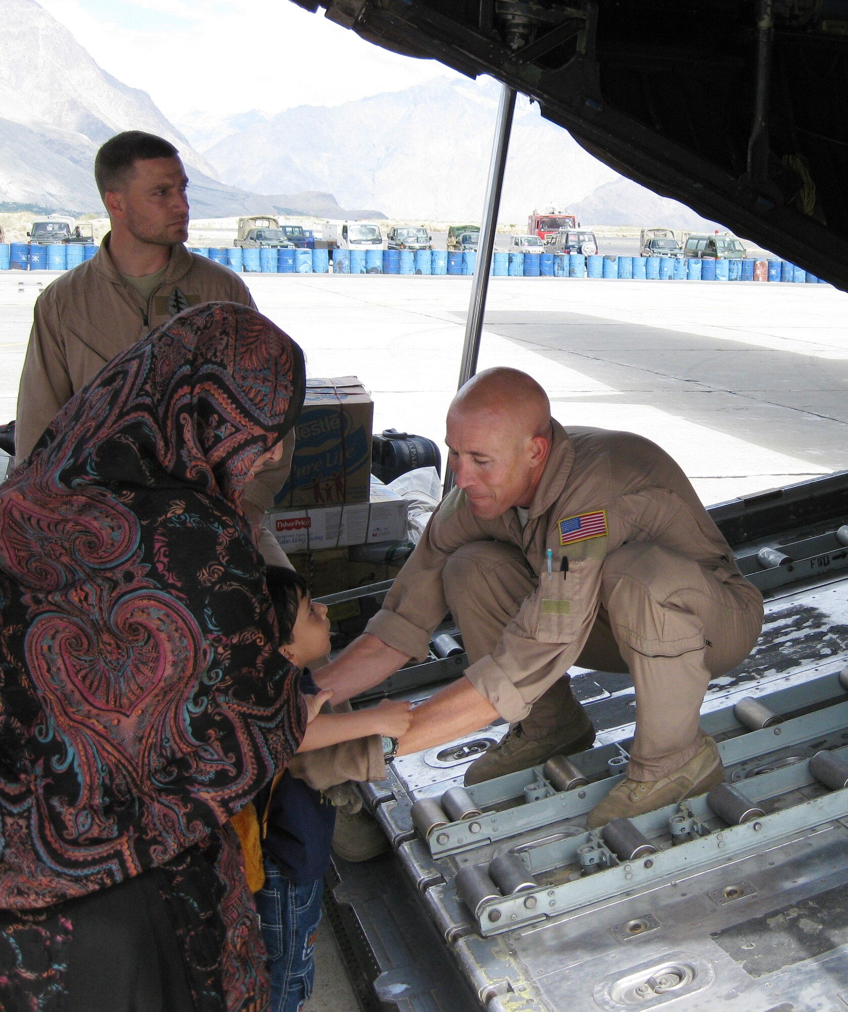 SOUTHWEST ASIA -- Tech. Sgt. Matthew Stiles, a flight engineer with the 737th Expeditionary Airlift Squadron helps a child board a C-130 aircraft at Skardu Airport, Pakistan, Sept. 5, for transportation to another location inside Pakistan. The child and his family are among millions of Pakistani citizens who were displaced from their homes following record flooding in July and August. The 737th EAS, along with Airmen from the 386th Expeditionary Air Wing, deployed multiple C-130 aircraft and more than 80 personnel in response to the disaster, airlifting more than 1,000 tons of relief supplies and 500 displaced persons between Aug. 30, 2010, and Oct. 1, 2010, when the squadron's role in the mission concluded.