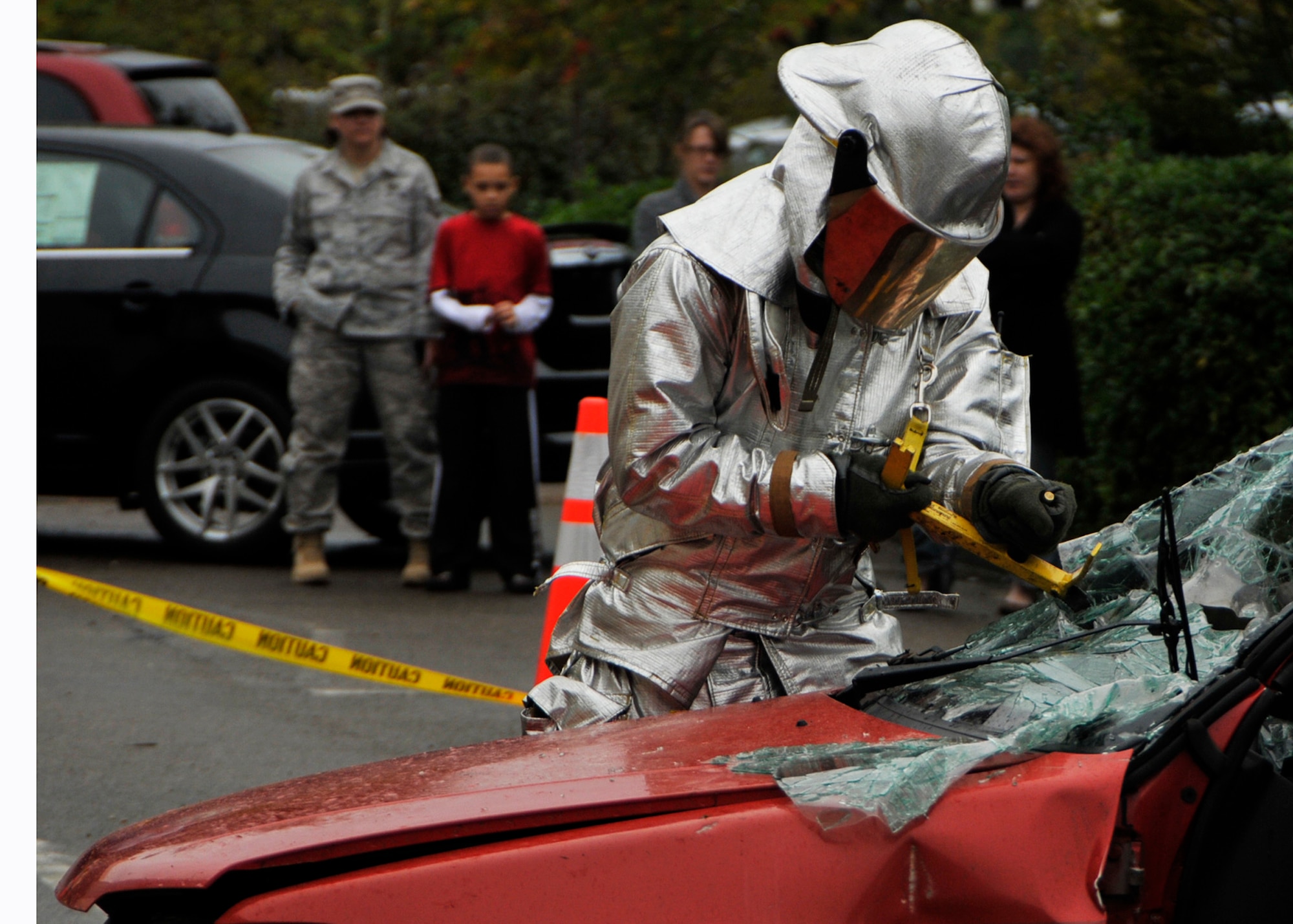 ROYAL AIR FORCE LAKENHEATH, England – Airman 1st Class Aaron Calvetti, 48th Civil Engineer Squadron firefighter, saws through the shattered windshield in preparation for removing the top portion of the wrecked car as Airmen and civilians watch during a vehicle extrication demonstration that is part of National Fire Prevention Week at the RAF Lakenheath Base Exchange on Oct. 6. The goal of the week is to help raise awareness of fire hazards and prevent fires from happening. (U.S. Air Force photo/Airman 1st Class Tiffany M. Deuel)