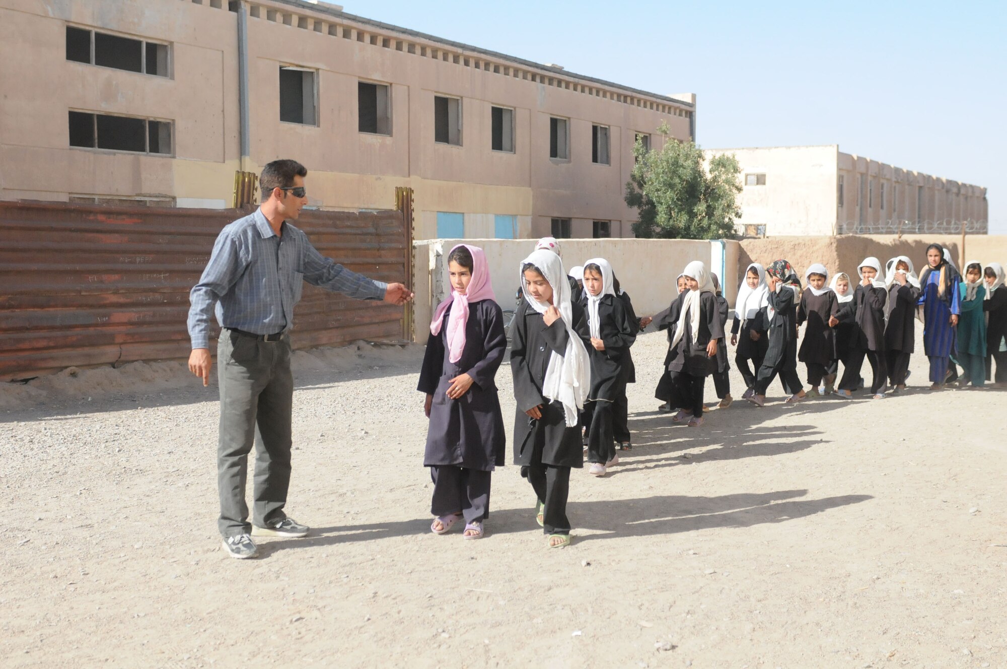 Shindand, Afghanistan – Female students walk to the front of the schoolhouse where Afghan Soldiers, Airman and US soldiers and airman pass out backpacks to the females that attend the school.  (U.S. Navy photo by Mass Communication Specialist 3rd Class Jared E. Walker/ RELEASED).