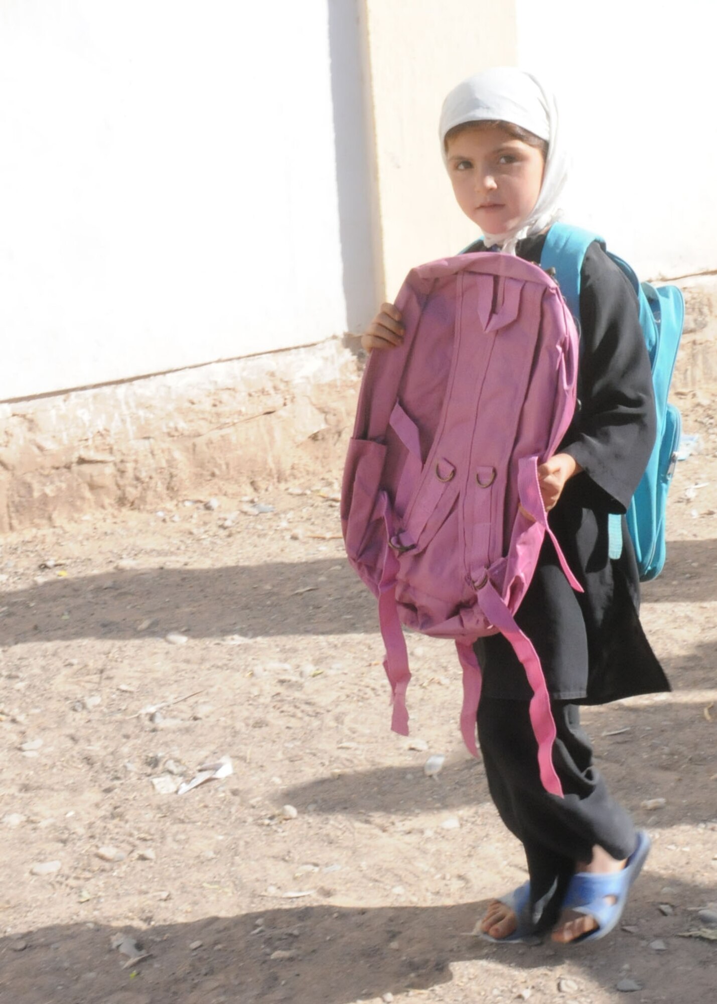 Shindand, Afghanistan – A female student receives a new backpack that has been handed out to her by the Soldiers and Airman of Shindand Air base during their mission to the female school in the nearby village. All the females from the surrounding villages attend the school with 1st grade through 12th grade being taught there. (U.S. Navy photo by Mass Communication Specialist 3rd Class Jared E. Walker/ RELEASED).