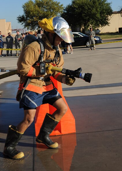 DYESS AIR FORCE BASE, Texas—Airman 1st Class Javier Hernandez, 7th Civil Engineer Squadron, prepares to shoot water out of a fire hose during a Firefighters Challenge here, Oct. 8. Firefighters from the 7 CES hosted an obstacle course challenge for Dyess Airmen as their final Fire Prevention Week event.  More than 40 teams participated in the event that consisted of six obstacles such as putting on bunker gear, carrying a fire hose up a flight of stairs and carrying a 175 pound dummy. (U.S Air Force photo/ Airman 1st Class Shannon Hall)