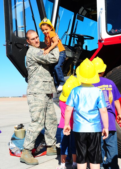DYESS AIR FORCE BASE, Texas--Staff Sgt. Daniel Newland, 7th Civil Engineer Squadron firefighter, helps a Merkel Elementary student down from a firetruck at the Fire Department here Oct. 8. Firefighters from the 7 CES gave kindergarteners from Merkel Elementary a tour of the fire department. Students also were given demonstrations by the dog handlers at the K-9 unit. Dyess hosts tours throughout the year that are open to the public. For more information on tours call the Public Affairs office at (325) 696-4820 (U.S. Air Force photo/Airman 1st Class Chelsea Cummings)