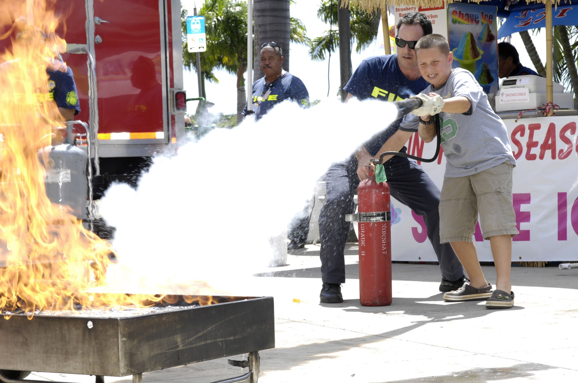 Ethan Shropshire, son of Intelligence Specialist Chiefs (ISC) John and Shannon Shropshire, extinguishes a fire during a live fire demo at the Navy Exchange Mall Complex Oct. 7.  The Federal Fire Department's Fire Prevention Division is increasing the public's awareness on the dangers of smoke and fire during Fire Prevention Week at Joint Base Pearl Harbor-Hickam, Hawaii.  (Photo by David D. Underwood, Jr.)