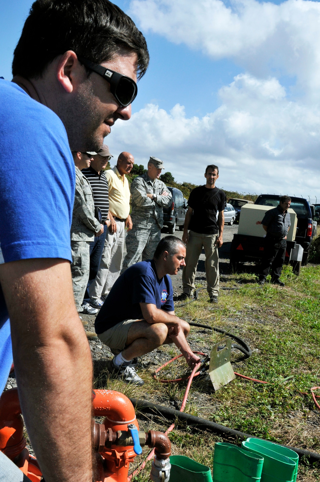 (Far left) Decio Avila and Jorge Arruda start a pump, which operates a boom and skimmer, during a land fuel spill training exercise, as other members observe  Sept. 29, 2010, at Lajes Field, Azores. The joint exercise brought together more than 40 U.S. and host nation emergency response team members in a classroom-discussion setting and hands-on scenarios. Mr. Avila and Arruda are from the 65th Civil Engineer Squadron. (U.S. Air Force photo/Staff Sgt. Olufemi Owolabi)