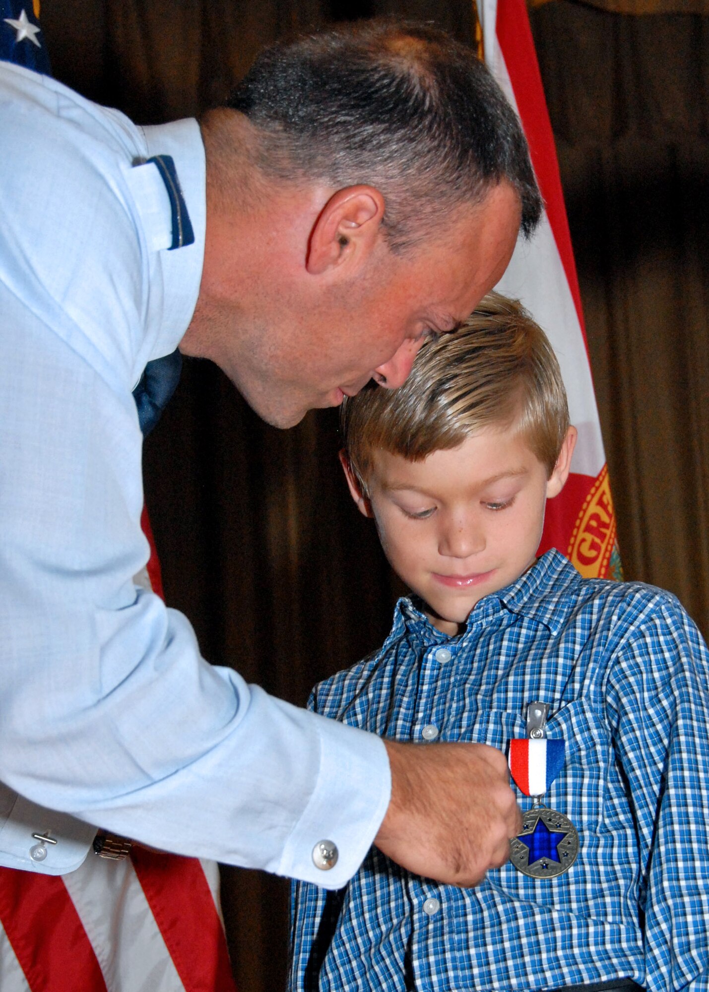 Col. Sal Nodjomian, commander of the 96th Air Base Wing, presents a "Home Front Hero" blue star medal to 7-year-old Riley Fitzner. The Home Front Hero award recognizes children for contributions to their parents' successes in the military. (U.S. Air Force photo/Sachel Seabrook) 
