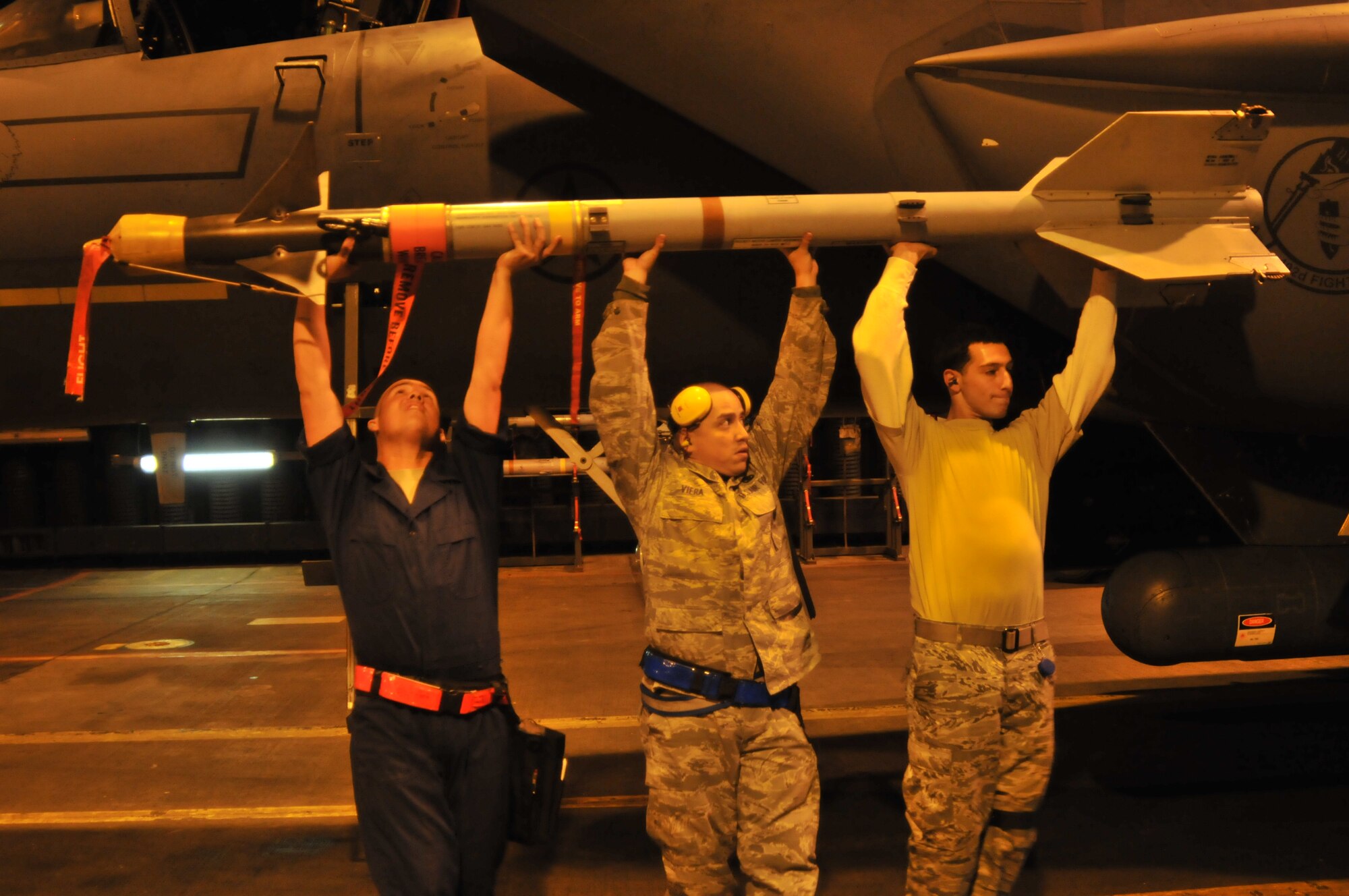 ROYAL AIR FORCE LAKENHEATH, England -- Tech. Sgt. Salvador Bravo, Staff Sgt. Jorge Viera and Senior Airman Alex Ponzi, 48th Maintenance Group weapons load team members, load an AIM-9 missile onto an F-15E Strike Eagle during a set piece demonstration Oct. 7. A five-man team inspected, refueled and rearmed the aircraft to practice for the upcoming NATO Tactical Evaluation. (U.S. Air Force photo/Senior Airman David Dobrydney)