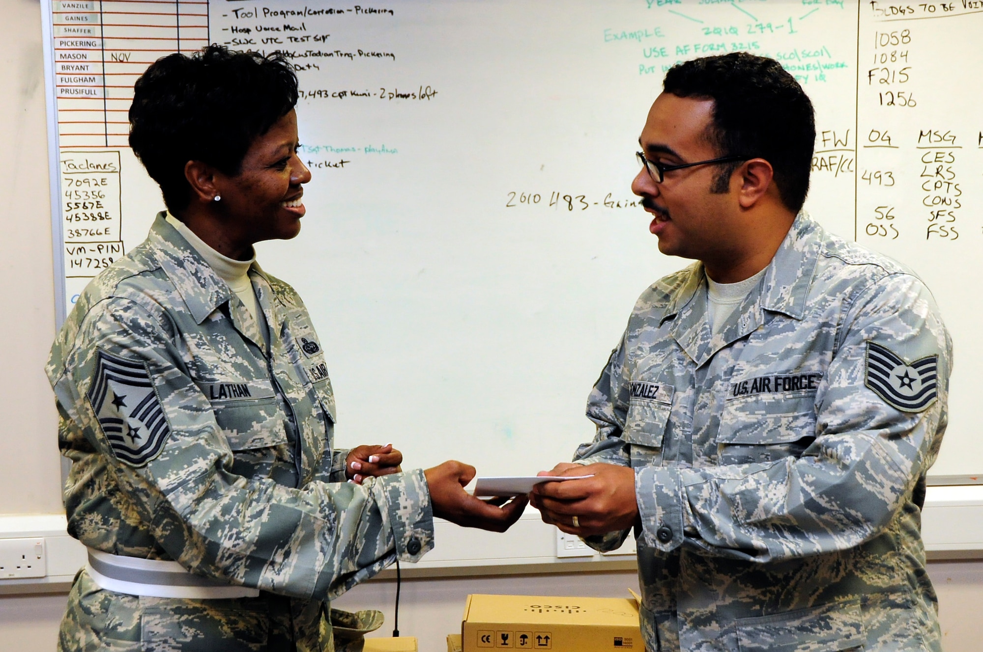 Chief Master Sgt. SaRita Lathan, 48th Fighter Wing command chief, presents Tech. Sgt. Julio Gonzalez, 48th Communications Squadron Secure Infrastructure NCO in charge, with a coin and letter from Retired Chief Master Sgt. Pamela Derrow, former United States Air Forces in Europe command chief, Oct. 8. Tech. Sgt. Julio Gonzalez was one of two Airmen from the Liberty Wing to be recognized by the former command chief for outstanding performance in their jobs. (U.S. Air Force photo/Airman 1st Class Eboni Knox)

