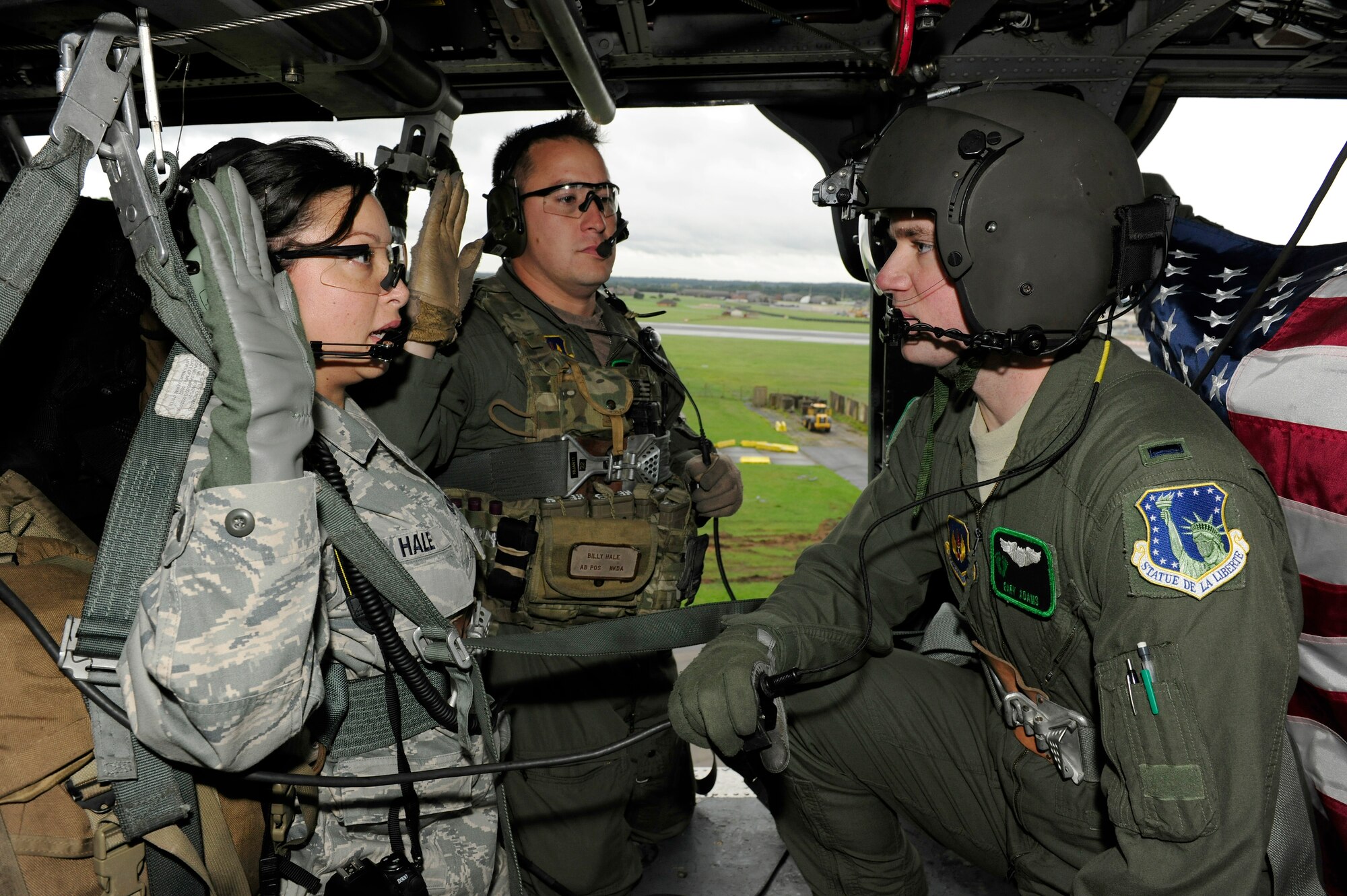 ROYAL AIR FORCE LAKENHEATH, England – 1st Lt. Gary Adams, 56th Rescue Squadron mobility officer in charge, administers the oath of enlistment to Tech. Sgt. Joanne Hale (left), 56th RQS NCO in charge of aircrew flight equipment, and her spouse Tech. Sgt. Billy Hale (middle), 56th Rescue Squadron aerial gunner, while hovering in an HH-60 Pavehawk helicopter Oct. 6.  For Tech Sgt. Billy Hale, this reenlistment will be his last one before retiring, and it’s only fitting that it’s with the same squadron he began his Air Force career with.  It also has special meaning to both sergeants that they can share in this together.  (U.S. Air Force photo/Staff Sgt. Connor Estes)