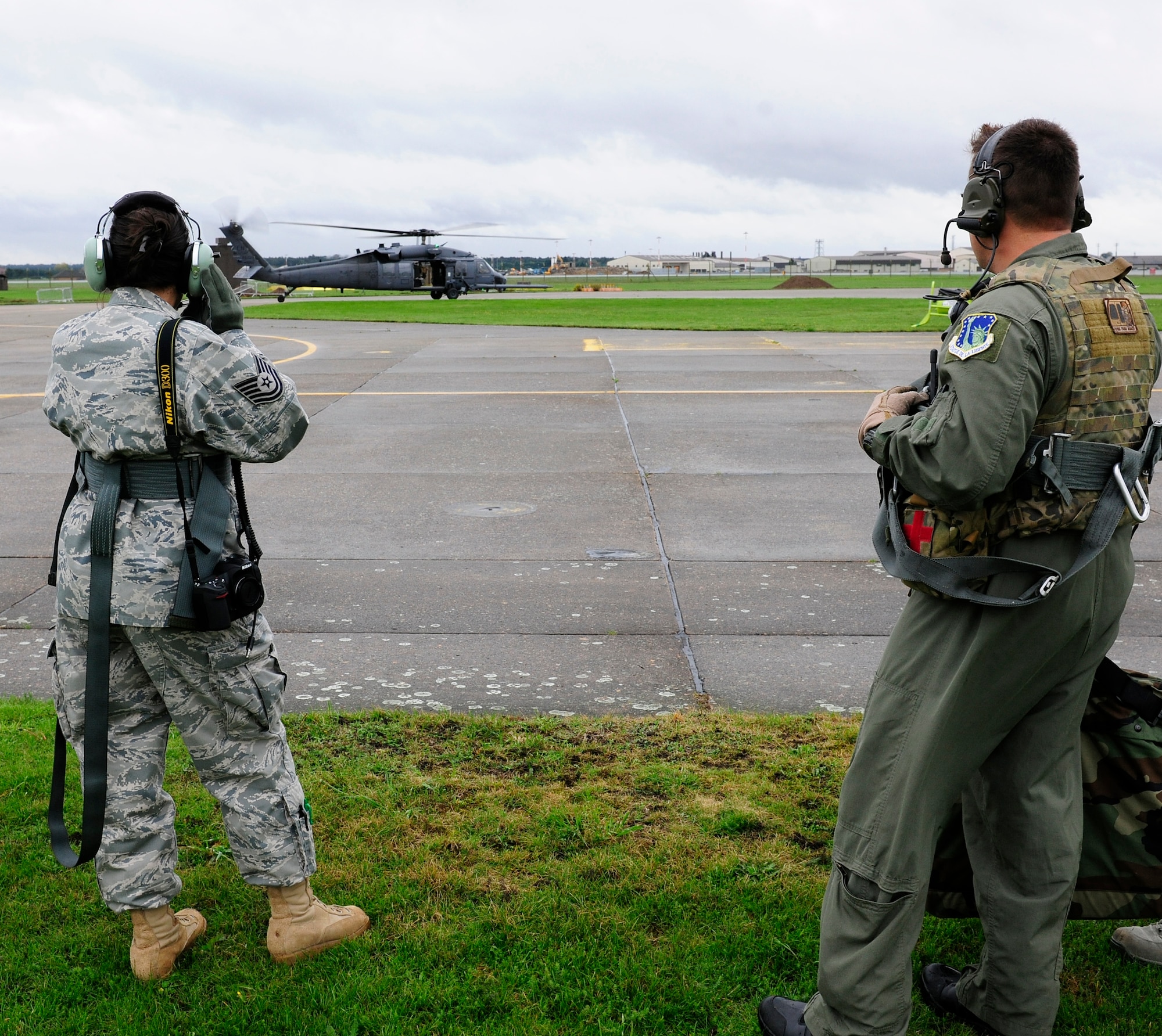 ROYAL AIR FORCE LAKENHEATH, England – Tech. Sgt. Joanne Hale (left), 56th RQS NCO in charge of aircrew flight equipment, and her spouse Tech. Sgt. Billy Hale (right), 56th Rescue Squadron aerial gunner, wait for the signal to board an HH-60 Pavehawk helicopter Oct. 6.  The two married sergeants reenlisted together while hovering over the base.  (U.S. Air Force photo/Staff Sgt. Connor Estes)