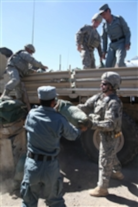 U.S. Army Sgt. Brian Bentley (right) and Spc. Zech Burke, both cavalry scouts with 1st Platoon, Bravo Troop, 1st Squadron, 172nd Cavalry Regiment, and Afghan National Police officers unload sandbags while visiting Jabal Saraj Afghan National Police Outpost in the Parwan province of Afghanistan on Oct. 3, 2010.  The regiment donated over 400 sandbags to increase the security of the outpost.  