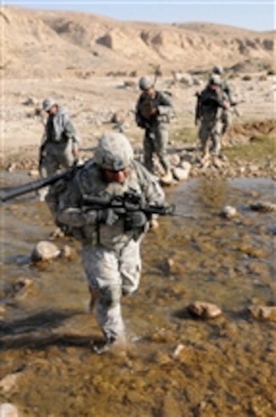 U.S. Army Sgt. Manuel Baeza (2nd from left) of Charlie Company, 1st Battalion, 4th Infantry Regiment clasps his carbine as he crosses a river during an area reconnaissance off Highway 1 in Zabul province, Afghanistan, on Oct. 1, 2010.  