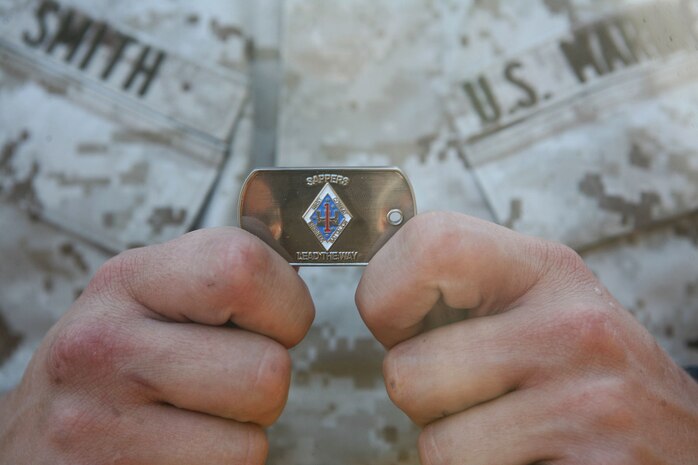 Pfc. Christopher M. Smith, a combat engineer with 1st Combat Engineer Battalion, 1st Marine Division, holds a 1st CEB Sapper coin given to him by Lt. Col. Andrew Niebel, commanding officer of 1st CEB, in front of the battalion’s headquarters building at the San Mateo training area Oct. 8. Niebel presented a coin to Smith and fellow Marines Anthony S. Roldan and Ryan J. Shuey, also combat engineers with 1st CEB, in recognition for their actions Oct. 6 when they assisted a police officer with the Long Beach Police Department who was violently attacked by a suspect yielding a knife. Smith is a 20-year-old from Lemoore, Calif.