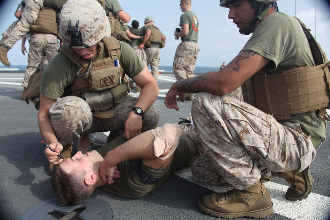 Lance Corporals Dominick Talio and Crecencio Alvarez mark that a combat tourniquet was placed on Lance Cpl. Joshua Tuttle, all infantrymen with 2nd Platoon, K Company, Battalion Landing Team 3/8, 26th Marine Expeditionary Unit,  while practicing combat life saving skills on the flight deck of USS Ponce in the U.S. Navy Fifth Fleet Area of Responsibility, Oct. 9, 2009. 26th MEU continues to support relief operations in Pakistan and is also serving as the U.S. Central Command theater reserve force as elements of the MEU conduct training and planned exercises.