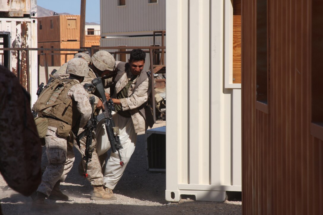 MARINE CORPS AIR GROUND COMBAT CENTER TWENTYNINE PALMS, Calif. – Marines with Company G, 2nd Battalion, 4th Marine Regiment, based out of Marine Corps Base Camp Pendleton, Calif., wrestle with a role player while conducting military operations on urbanized terrain training at Combat Center Range 215 Oct. 11 during exercise Steel Knight, a combined arms exercise incorporating more than 5,000 Marines and sailors. (U.S. Marine Corps photo by Lance Cpl. William J. Jackson)::r::::n::