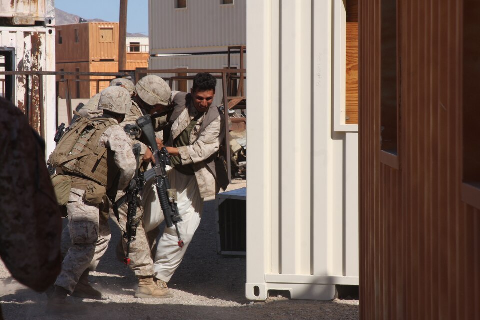 MARINE CORPS AIR GROUND COMBAT CENTER TWENTYNINE PALMS, Calif. – Marines with Company G, 2nd Battalion, 4th Marine Regiment, based out of Marine Corps Base Camp Pendleton, Calif., wrestle with a role player while conducting military operations on urbanized terrain training at Combat Center Range 215 Oct. 11 during exercise Steel Knight, a combined arms exercise incorporating more than 5,000 Marines and sailors. (U.S. Marine Corps photo by Lance Cpl. William J. Jackson)::r::::n::