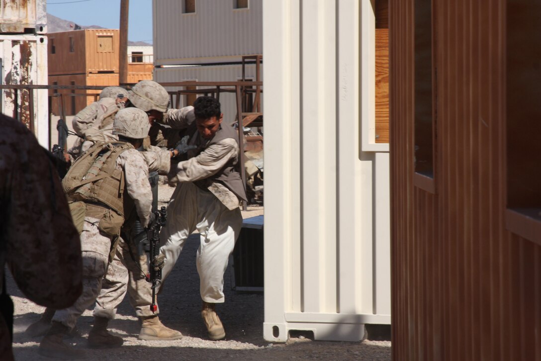 MARINE CORPS AIR GROUND COMBAT CENTER TWENTYNINE PALMS, Calif. – Marines with Company G, 2nd Battalion, 4th Marine Regiment, based out of Marine Corps Base Camp Pendleton, Calif., wrestle with a role player while conducting military operations on urbanized terrain training at Combat Center Range 215 Oct. 11 during exercise Steel Knight, a combined arms exercise incorporating more than 5,000 Marines and sailors. (U.S. Marine Corps photo by Lance Cpl. William J. Jackson)::r::::n::